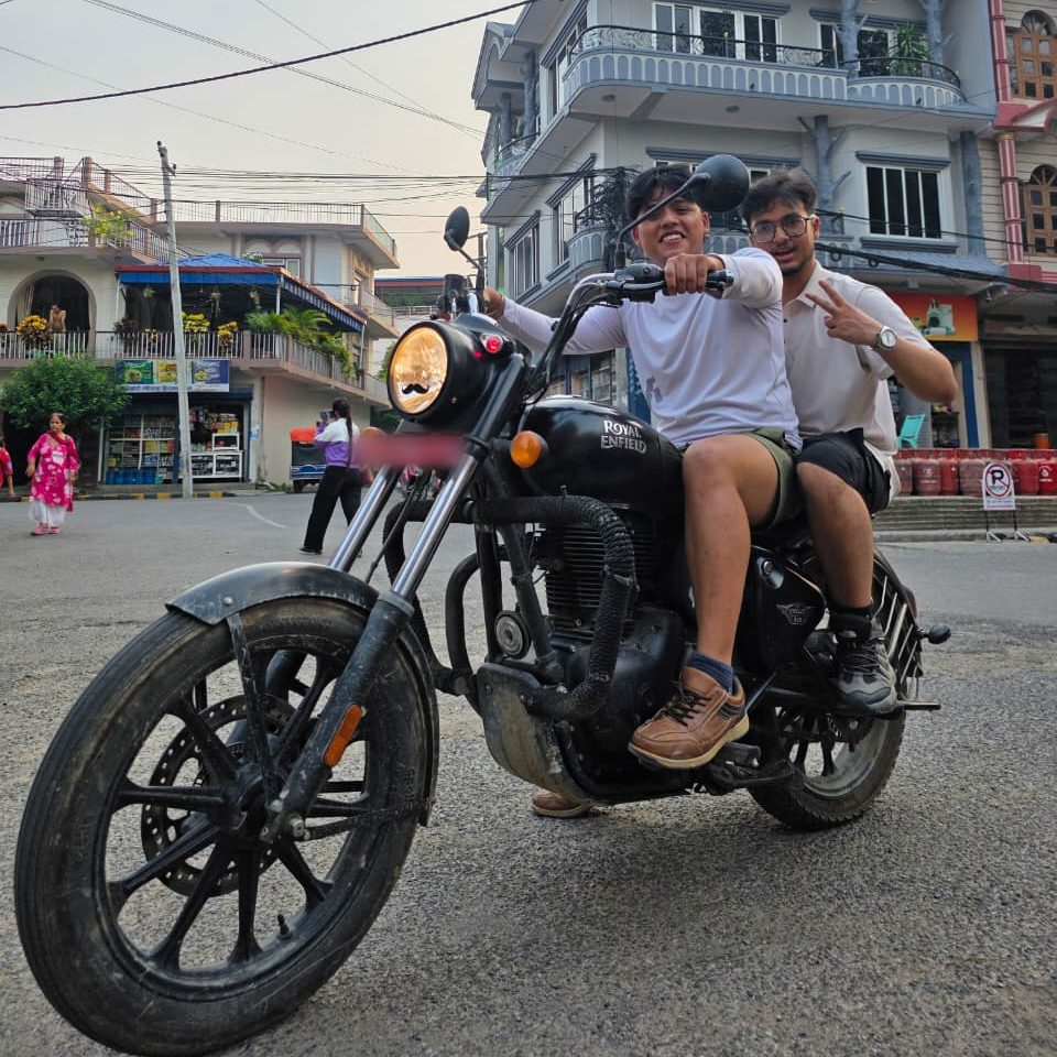 Kaustuv Batajoo and Bibidh Gautam riding a Royal Enfield motorcycle on a street in Nepal